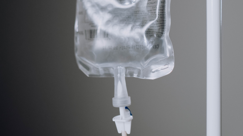 A black and white photo of an IV bag hanging on a pole.