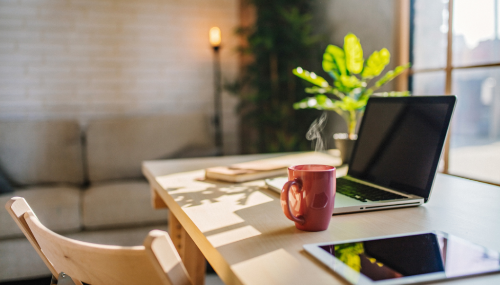 A desktop with a red coffee mug and an open laptop.