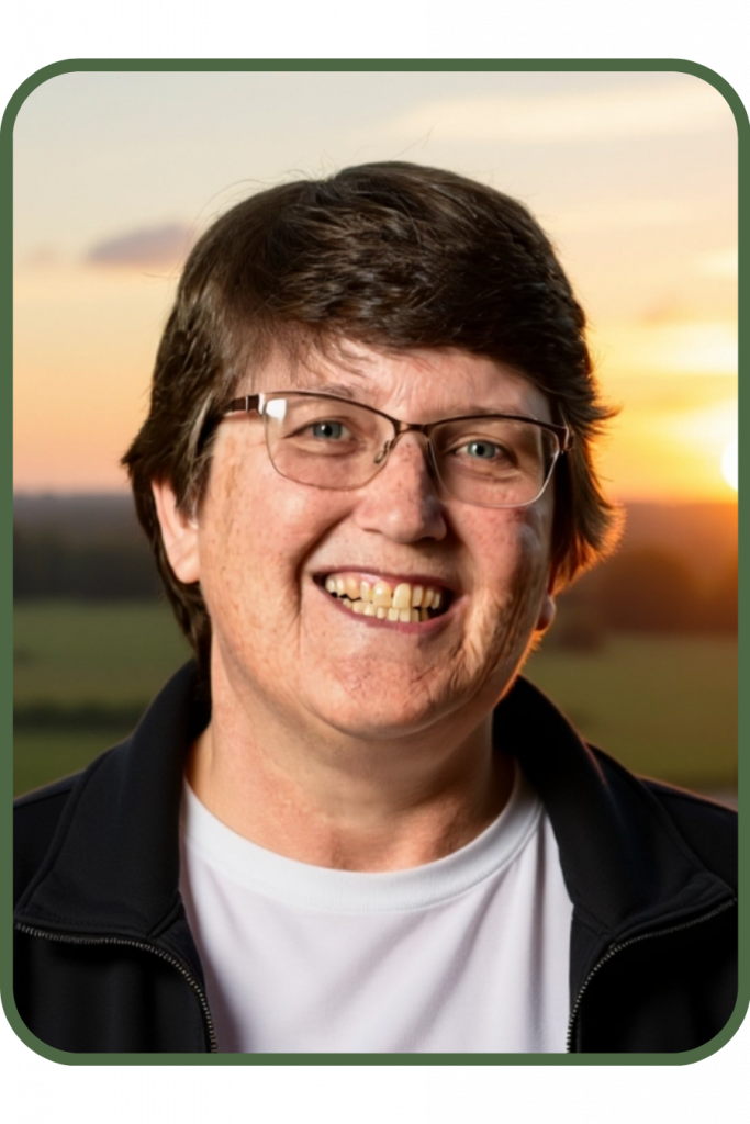 A woman with short brown hair wearing glasses is smiling at the camera.
