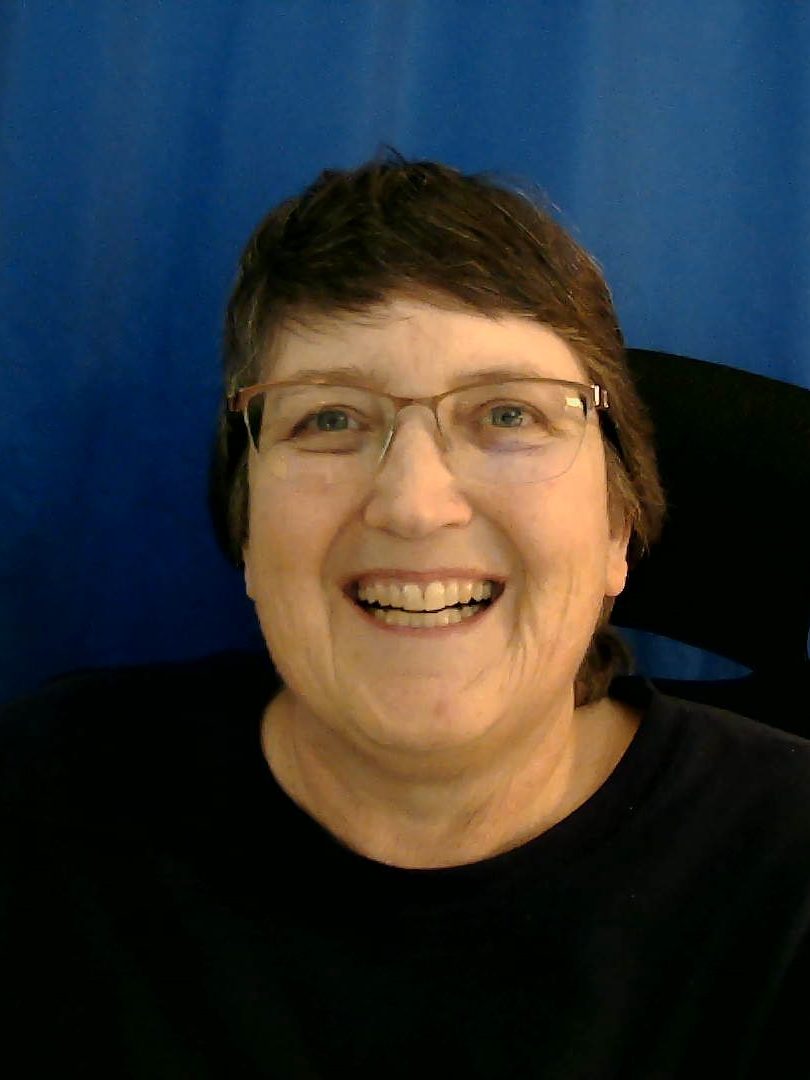 A photo of a woman with short brown hair wearing glasses and smiling at the camera.