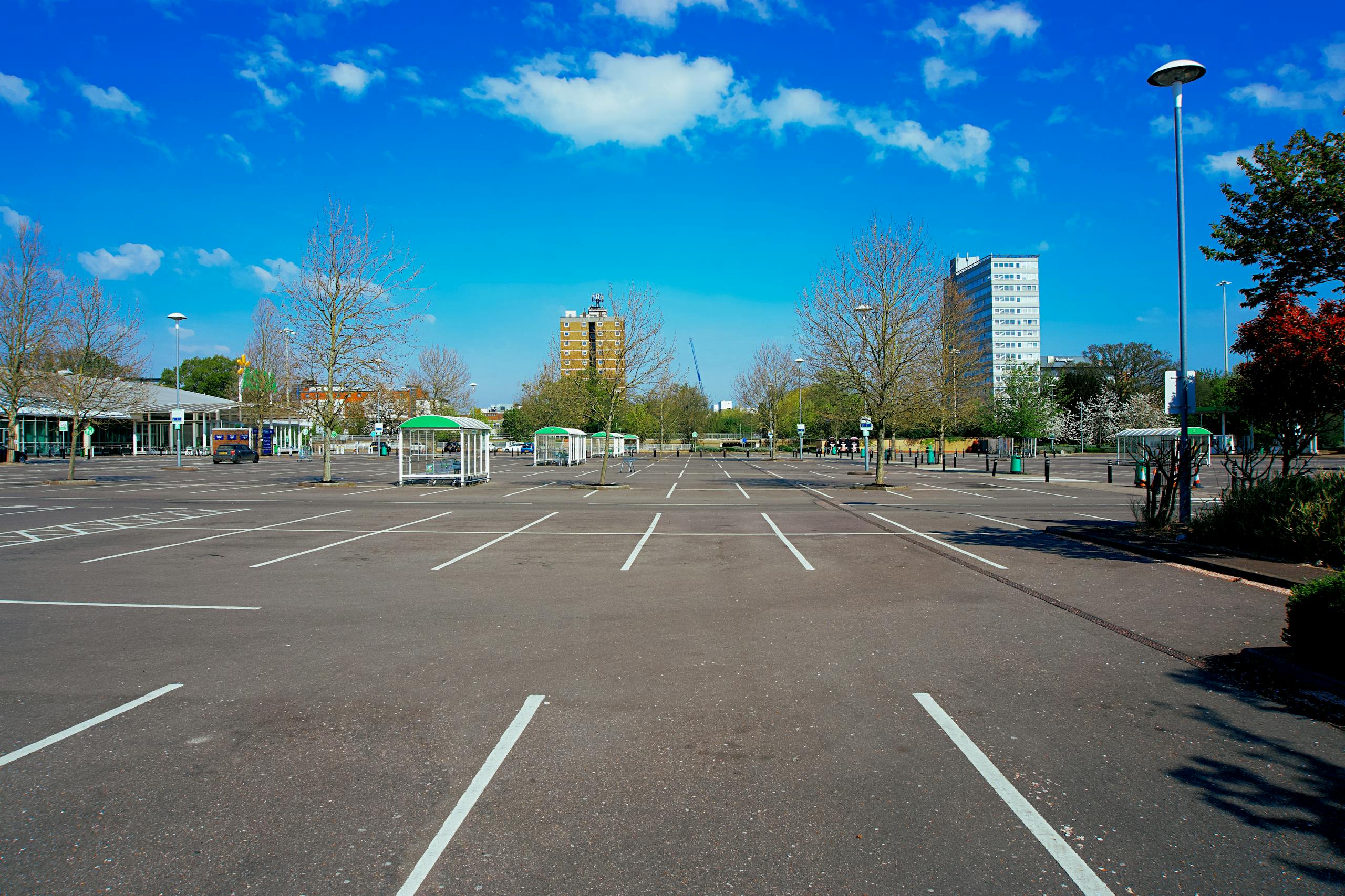 A deserted parking lot under a vivid blue sky in England, showcasing urban isolation.